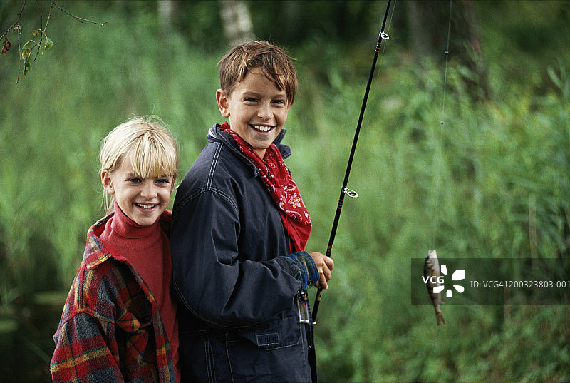 男孩和女孩(6-9岁)用钓鱼竿钓鱼图片素材