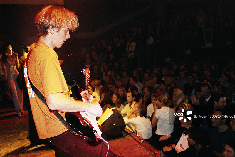在音乐会上弹电吉他的青少年男孩，侧视图图片素材
