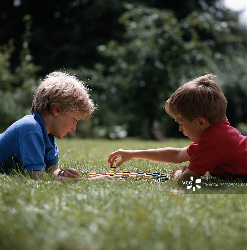 在花园里下跳棋的男孩 (8-9岁)，地面视角图片素材