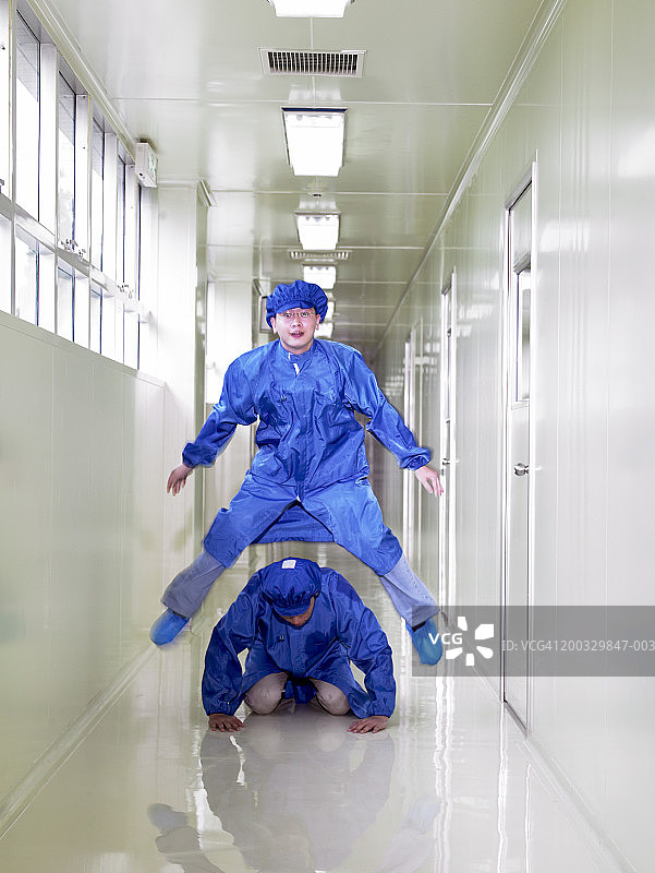 身穿防护服的两名研究人员在走廊里玩跳山羊图片素材