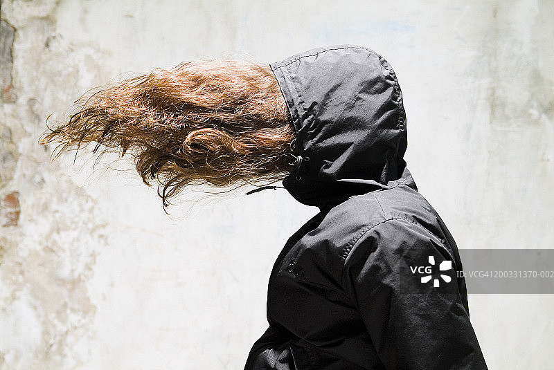 戴着帽子，头发散落遮住脸庞，侧脸的女人图片素材