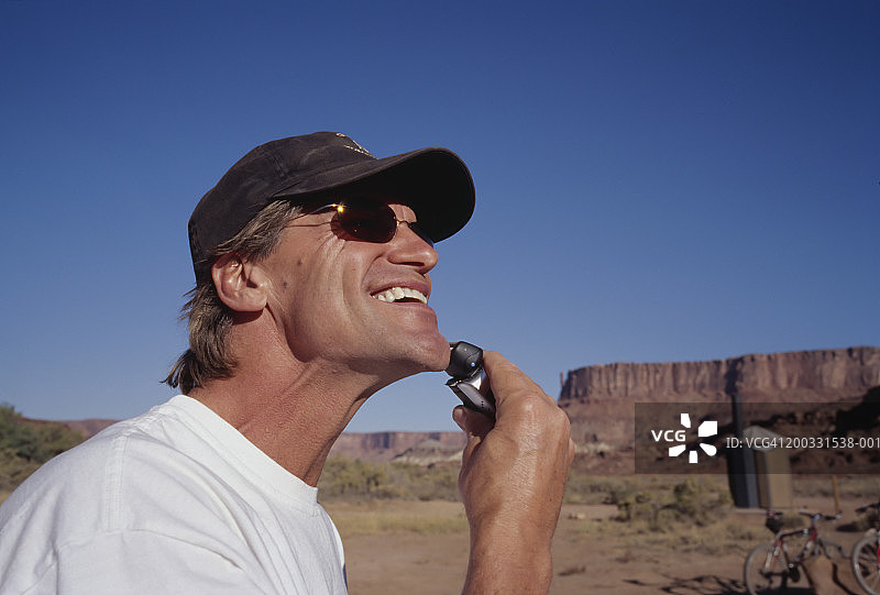 中年男人在户外用电动剃须刀刮胡子（侧面视角）图片素材