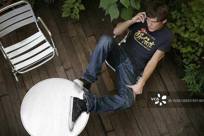 年轻男人在露台上使用手机，俯视角度图片素材