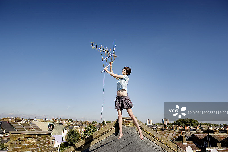 年轻女人在屋顶上举起天线图片素材
