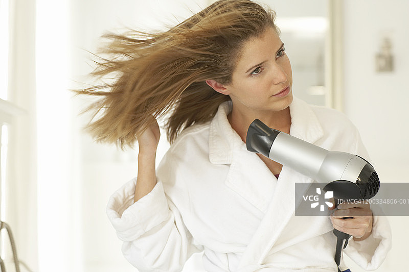 年轻女子穿着睡袍吹干头发图片素材