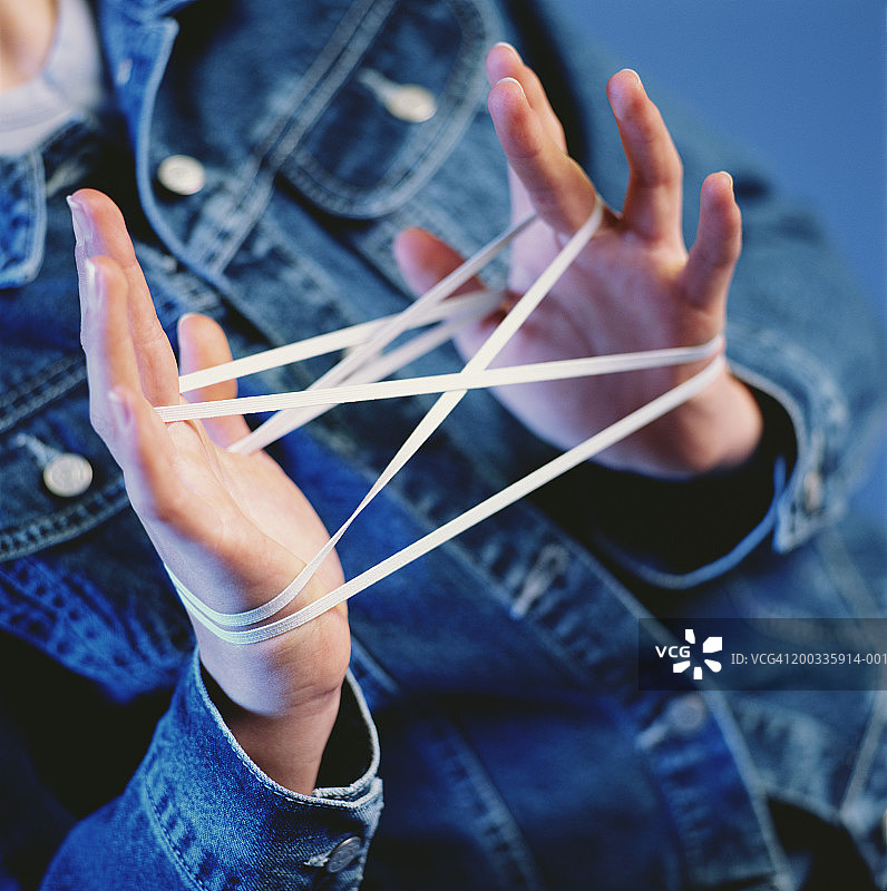 女人用橡皮筋做翻绳游戏，手部特写图片素材