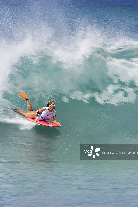 在海浪中玩趴板的年轻女人图片素材