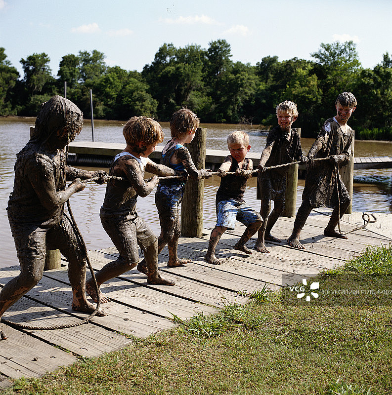 在湖边玩拔河的满身泥土的男孩（3-10岁）图片素材