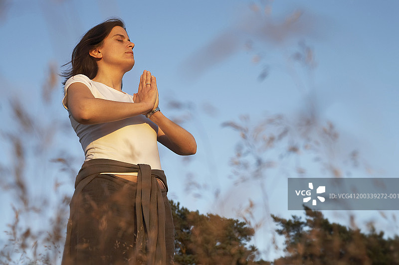 山式，手在合十，闭着眼睛的女人，低角度视图图片素材