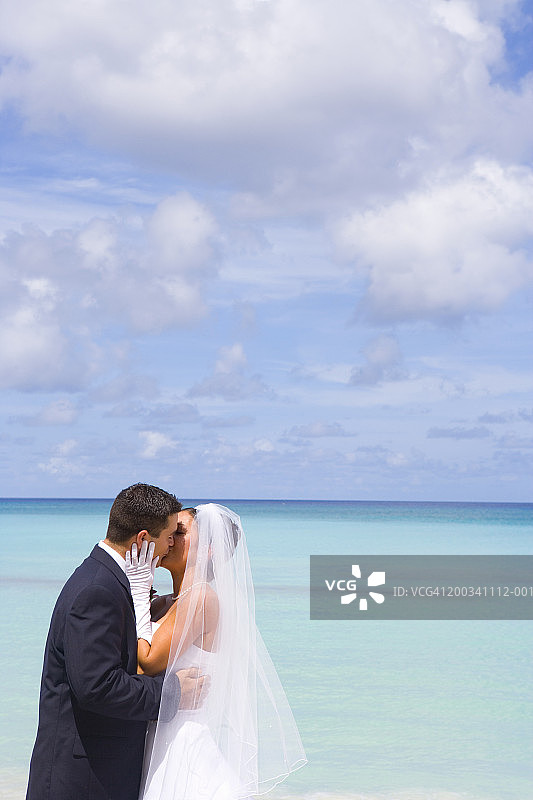 开曼群岛大开曼岛海滩上接吻的新娘和新郎图片素材