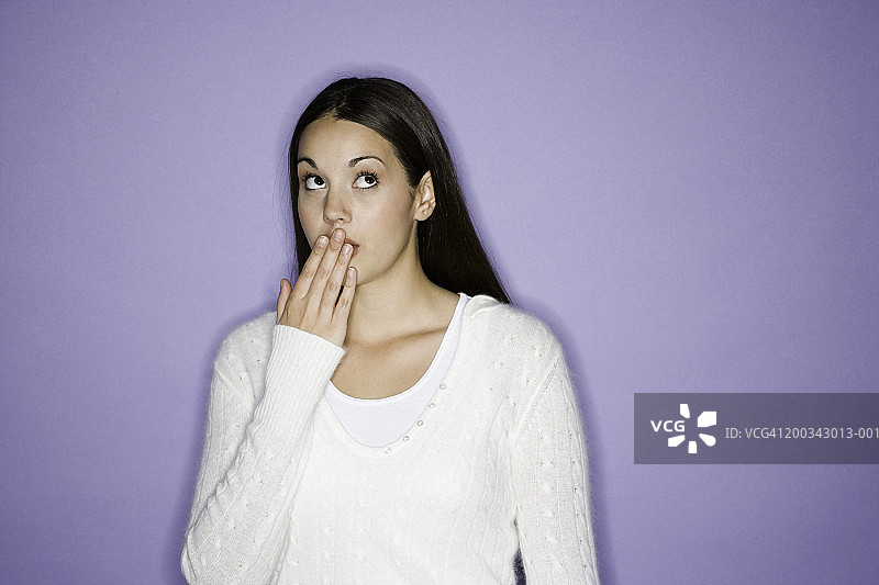 年轻女人抬头向上看，手捂着嘴图片素材