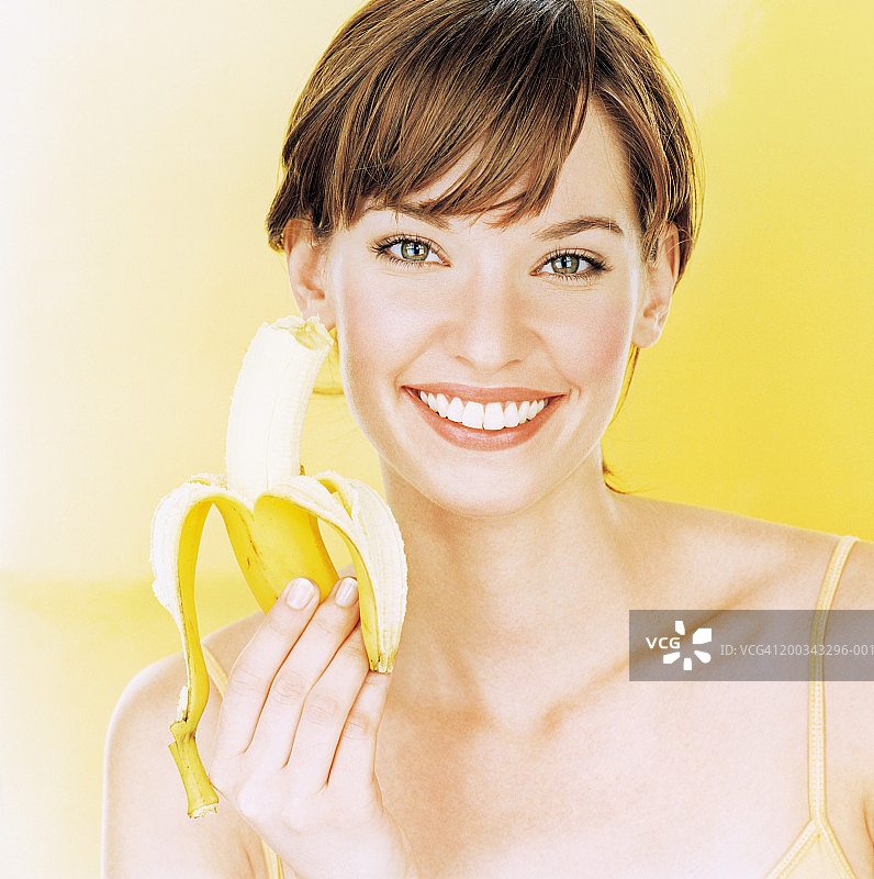 手拿香蕉微笑的年轻女人特写图片素材