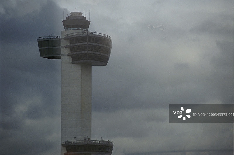 空中交通管制塔台，背景中有飞机起飞图片素材