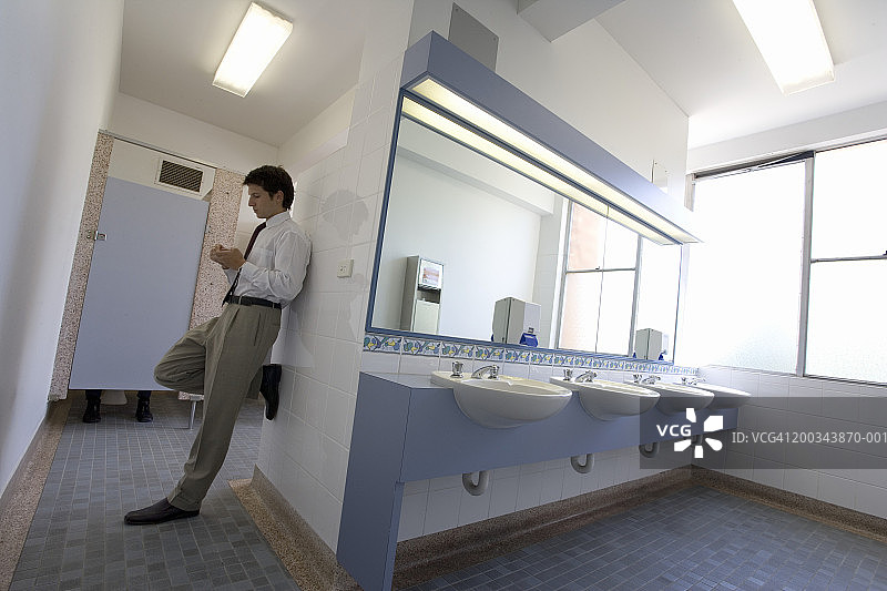 靠在洗手间墙壁上的商人图片素材