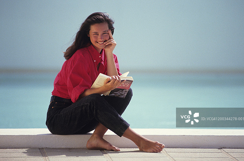 年轻女子坐在海边看书肖像图片素材