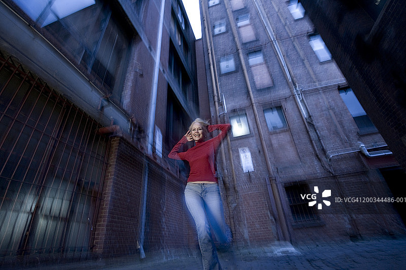 在小街道上奔跑的年轻女人（低角度视角，动态模糊）图片素材