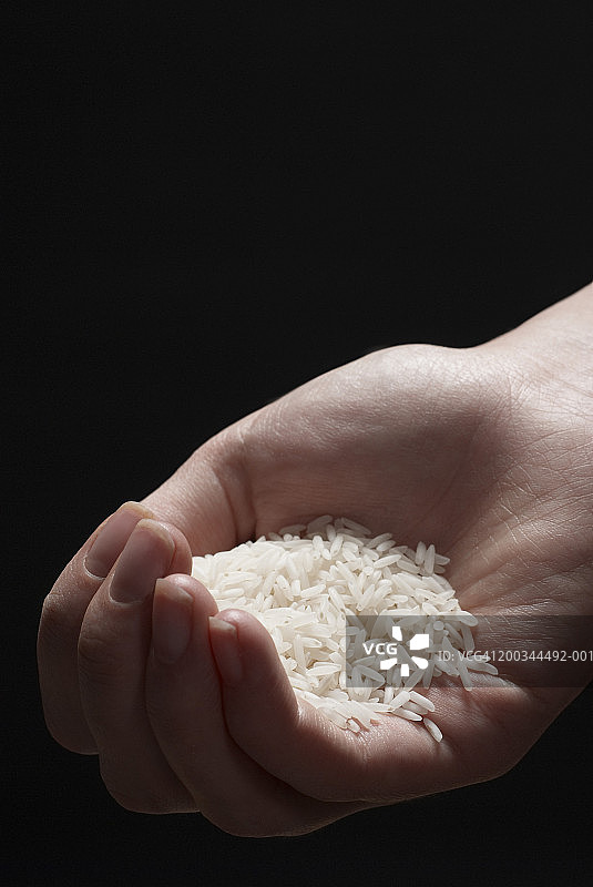 年轻女子手里捧着白米，凑近了图片素材