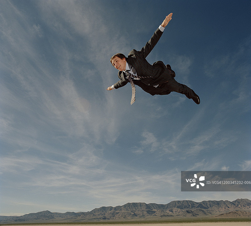 年轻商人面带微笑地飞过天空（侧视图）图片素材
