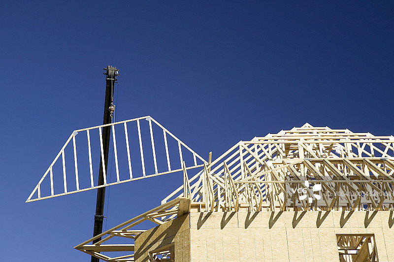 起重机吊起在建房屋的屋顶框架图片素材