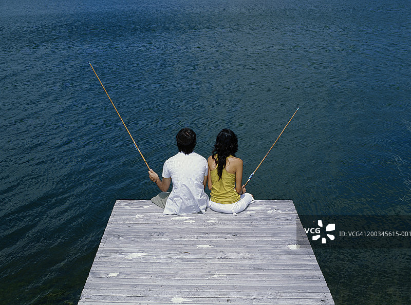 年轻男人和女人在码头钓鱼（后视图）图片素材