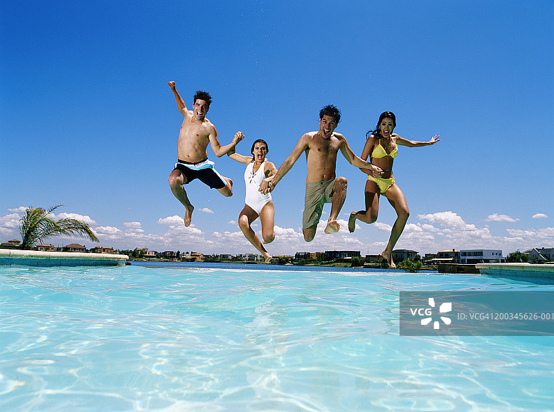 四个年轻人手牵手跳入无边泳池图片素材