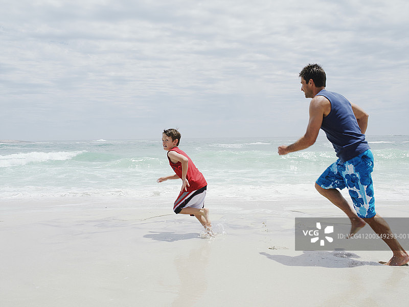 父亲在海滩上追逐儿子（9-11岁）图片素材