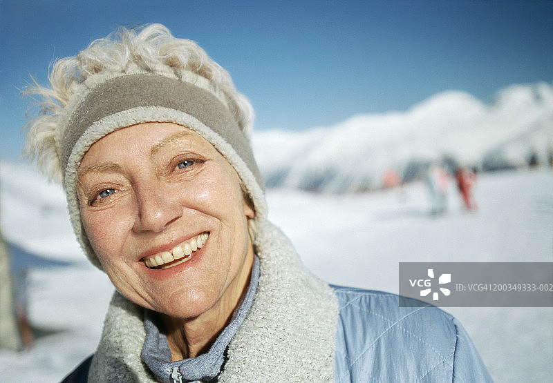 在高山滑雪坡上微笑的高龄妇女肖像图片素材
