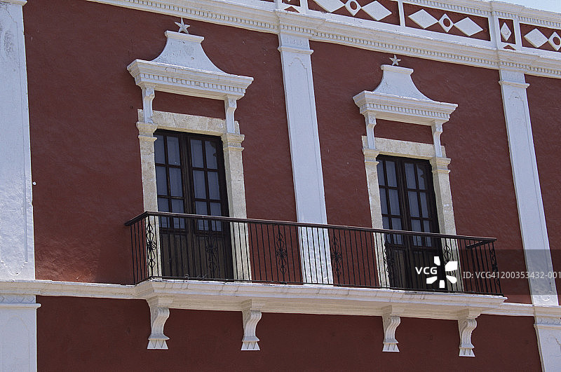 墨西哥坎佩切深红色建筑上的窗户，白色装饰，16至17世纪西班牙殖民建筑风格图片素材