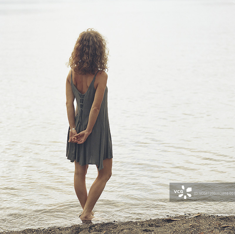 站在水边，双手合十的年轻女子（背影）图片素材