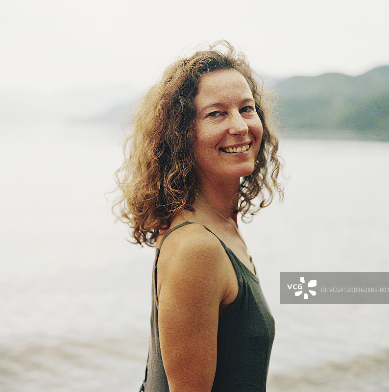 湖边微笑的年轻女人侧面肖像图片素材