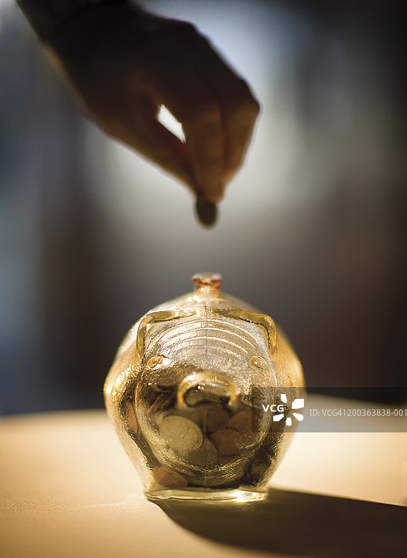 男人把硬币放进玻璃存钱罐里，特写（柔焦）图片素材