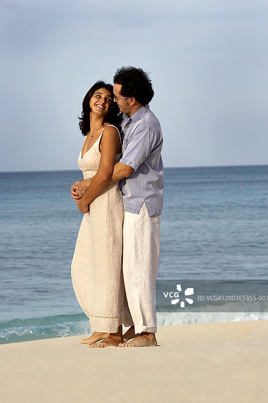 情侣在海滩拥抱的侧面照图片素材