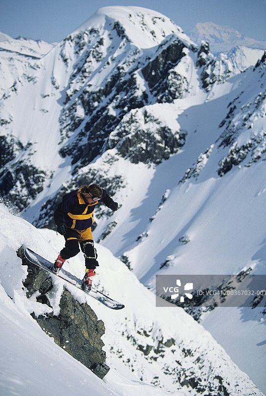 滑雪者飞跃阿拉斯加楚加奇山脉的岩石图片素材