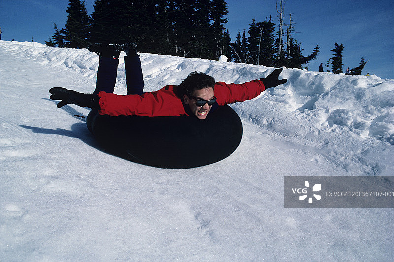 男子在美国华盛顿的雪山上乘坐充气内胎滑下图片素材