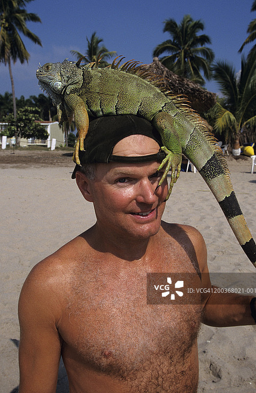 海滩上头顶鬣蜥的男人肖像图片素材