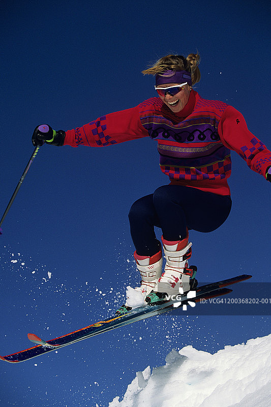 女滑雪者从雪堆上跳下，美国加利福尼亚州柯克伍德滑雪场图片素材