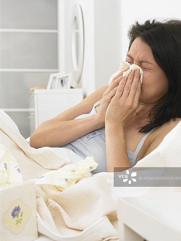 在床上擤鼻涕的年轻女子图片素材
