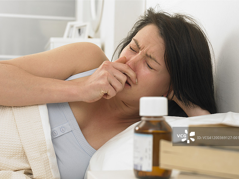 年轻女子在床上打喷嚏图片素材