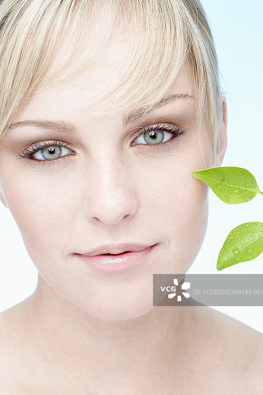 脸旁有榕树叶的微笑年轻女子特写肖像图片素材