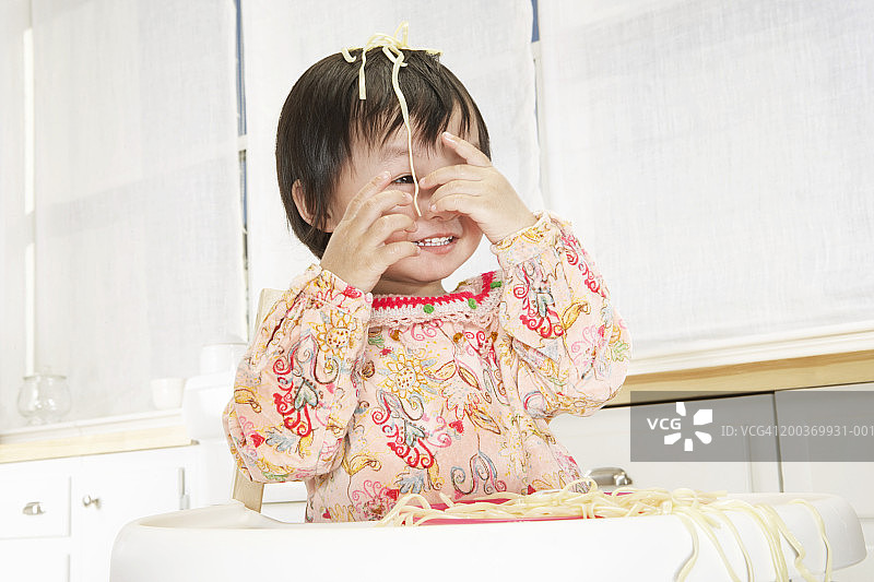 幼儿女孩（21-24个月）头发上有意大利面，微笑，特写图片素材