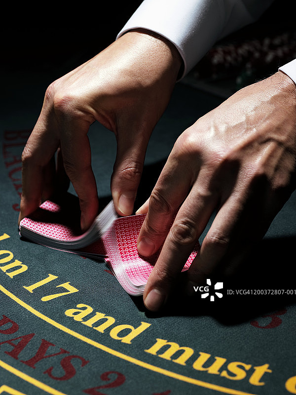 男性庄家在赌桌上洗牌特写图片素材
