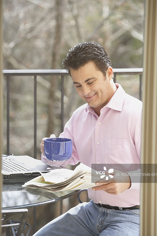 拿着报纸和咖啡杯的中年男人图片素材