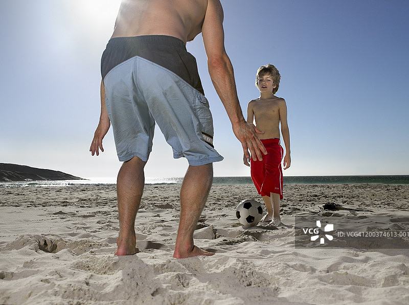 父子在沙滩上踢足球图片素材