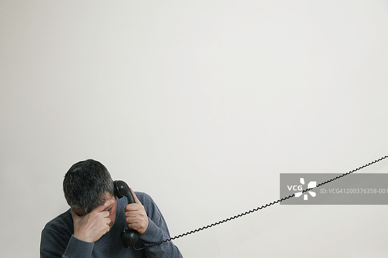 男人坐在楼梯上打电话，手扶额头图片素材