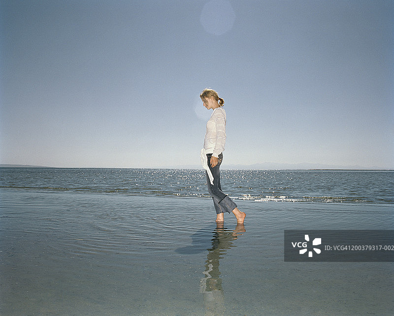年轻女人在海边行走，侧视图图片素材