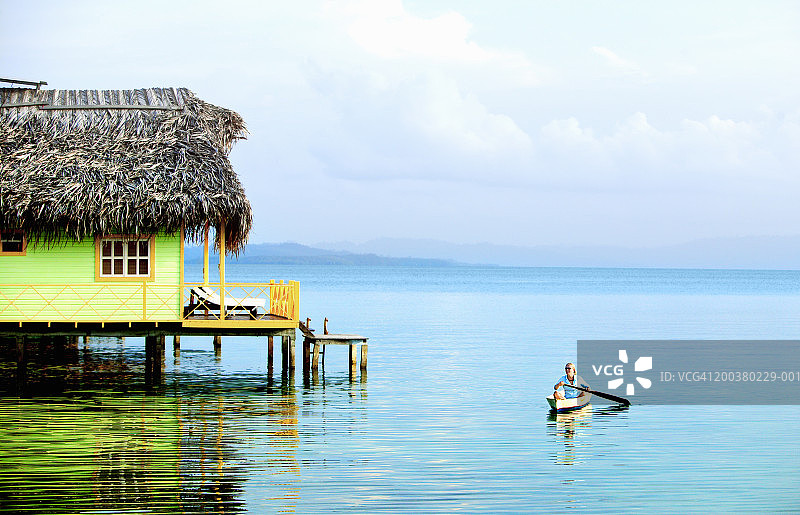 划独木舟经过平房的女人图片素材
