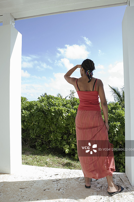 在阳台上向外看的年轻女人（后视图）图片素材