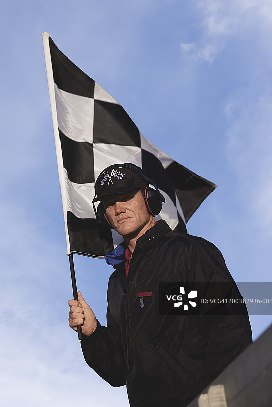 男性赛事官员手持方格旗的低角度肖像图片素材