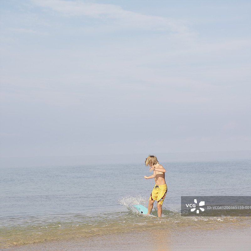 侧身站立在冲浪板上的青少年男孩（12-14岁）图片素材