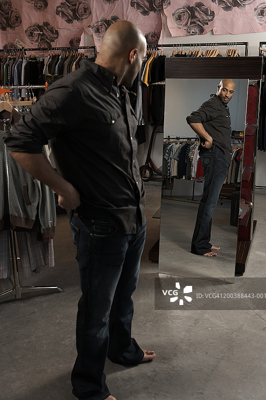 男人在零售店照镜子（侧视图，焦点在镜子上）图片素材